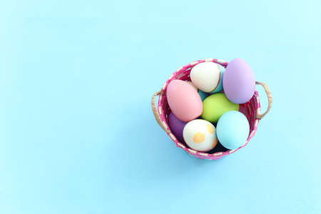 Cute bunny next to easter colorful eggs over pastel backgroundの写真素材