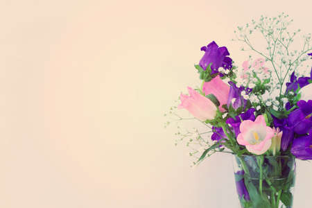 spring bouquet of purple, white and pink bell flowers over purple wooden background
