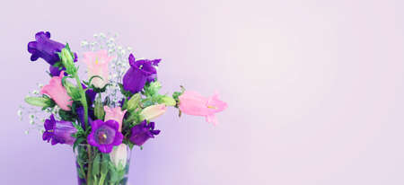 spring bouquet of purple and pink bell flowers over purple wooden backgroundの写真素材