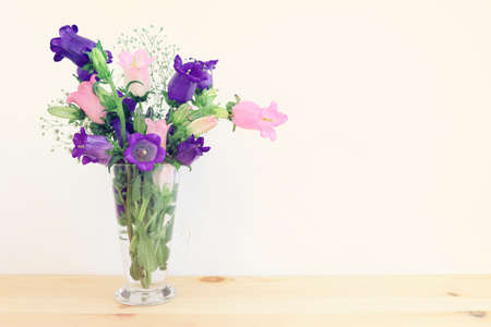 spring bouquet of purple and pink bell flowers over purple wooden backgroundの写真素材