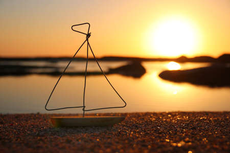 nautical concept with sail boat infront of sunset sea and beach landscapeの写真素材