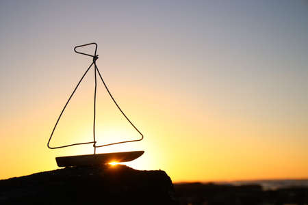 nautical concept with sail boat infront of sunset sea and beach landscapeの写真素材