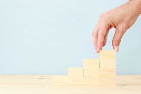 Hand arranging wood block stacking as chart or ladder. concept for growth and successの写真素材