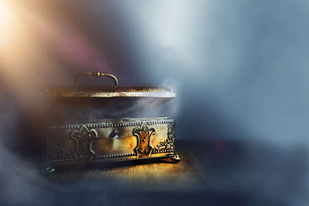 Image of mysterious magical treasure chest with light over wooden old table and dark backgroundの写真素材