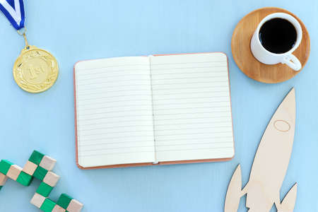 top view image of open notebook with blank pages next to cup of coffee on wooden table. ready for...