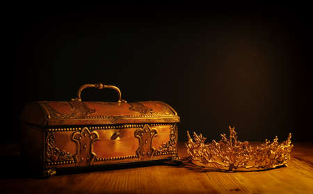 low key image of beautiful queen or king crown over gold treasure chest. vintage filtered. fantasy medieval periodの写真素材