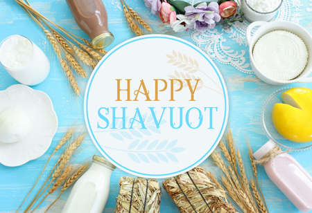 Top view photo of dairy products over blue wooden background. Symbols of jewish holiday - Shavuot