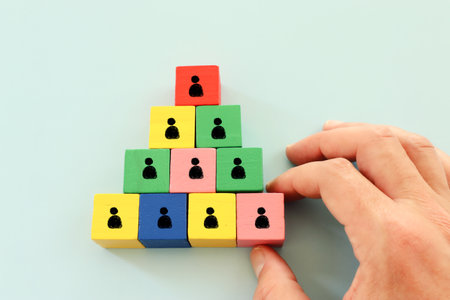image of tangram puzzle blocks with people icons over wooden table ,human resources and management...