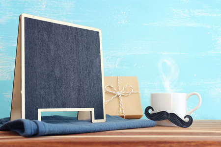 image of fathers day composition with hot cup of coffee and blackboard over tableの写真素材