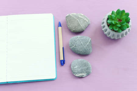 Empty open notebook and zen pebbles on pastel wooden background. copy space for text