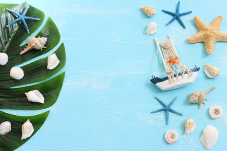 nautical concept with white decorative sail boat, seashells over blue wooden backgroundの写真素材