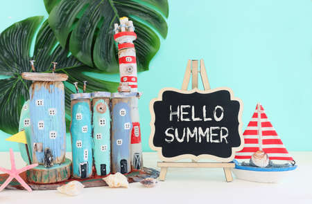 Nautical concept with sea life style objects as boat, driftwood beach houses, seashells and starfish over wooden table and blue backgroundの写真素材