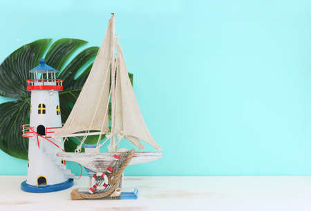 nautical concept with white decorative sail boat, lighthouse over wooden table and blue backgroundの写真素材
