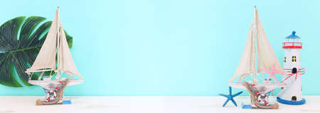 nautical concept with white decorative sail boat, seashells over wooden table and blue backgroundの写真素材
