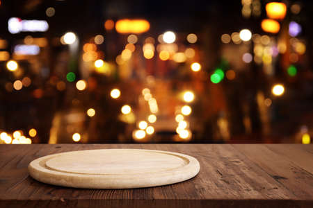 background Image of wooden table in front of abstract blurred restaurant lightsの写真素材
