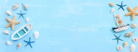 nautical concept with white decorative sail boat, seashells over blue wooden backgroundの写真素材