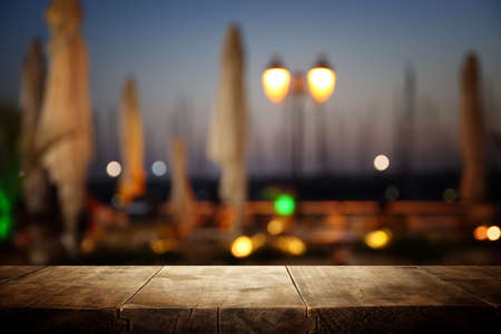 background Image of wooden table in front of abstract blurred restaurant lights