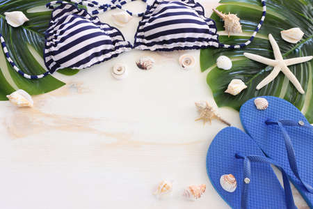 Top view of female swimsuit bikini, sea shells and starfish over white wooden background. Summer...