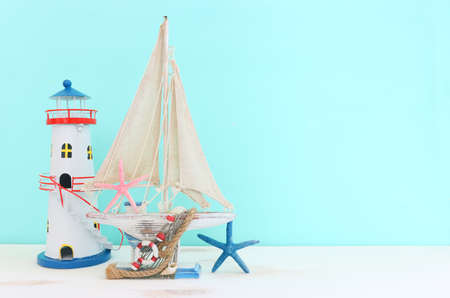 nautical concept with white decorative sail boat, seashells over wooden table and blue backgroundの写真素材