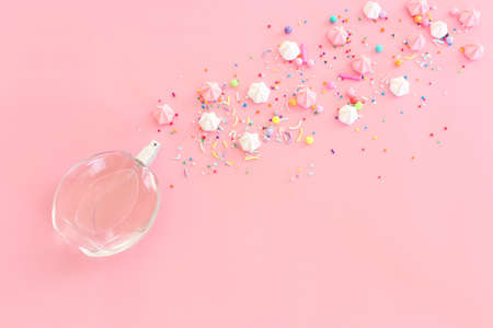 Top view of perfume bottle with candies and meringue over pastel pink background. Cosmetics, fragrance and perfumery conceptの写真素材