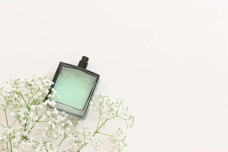 Top view of elegant perfume bottle with flowers over wooden white background. Cosmetics, fragrance...