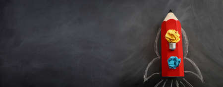 Education concept image. Creative idea and innovation. Crumpled paper as light bulb metaphor and rocket from pencil over blackboardの写真素材