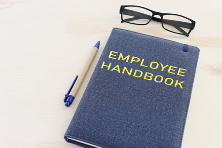 Concept image of employee handbook over wooden office table. top view