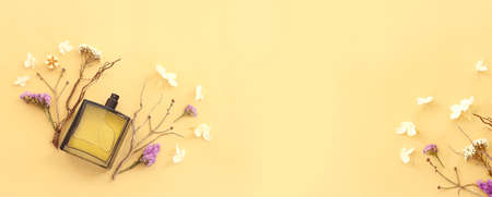 Top view of elegant perfume bottle with flowers and oud over yellow background. Cosmetics, fragrance and perfumery conceptの写真素材