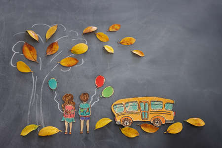 Back to school concept. Top view banner of school bus next to tree sketch with autumn dry leaves and kids over classroom blackboard backgroundの写真素材