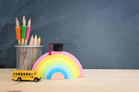 education and back to school concept. Stationery over wooden table in front of classroom blackboard