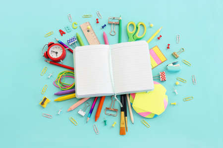 Back to school concept. Top view image of open empty notebook and student stationery over pastel...