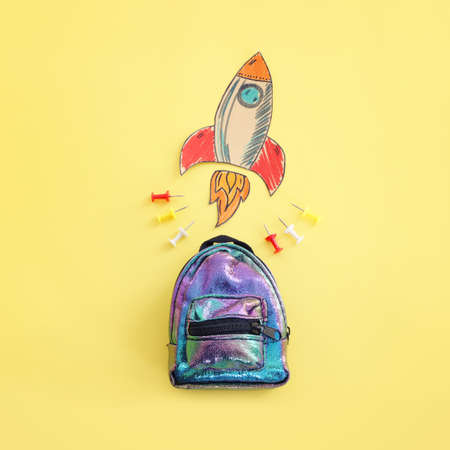 Back to school concept. Top view image of bag and space ship over pastel yellow backgroundの写真素材