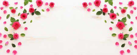 White wooden delicate background with pink roses and petals. Top view