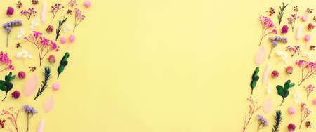 Top view image of pink, purple and green flowers composition over pastel yellow background .Flat lay
