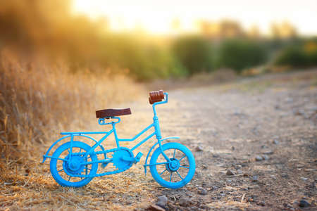 Blue vintage bicycle toy waiting outdoors at sunset lightの写真素材