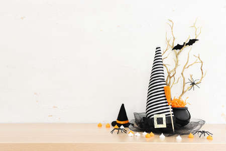 Halloween holoday. witcher cauldron and hat, broom, bare trees, treats over wooden tableの写真素材