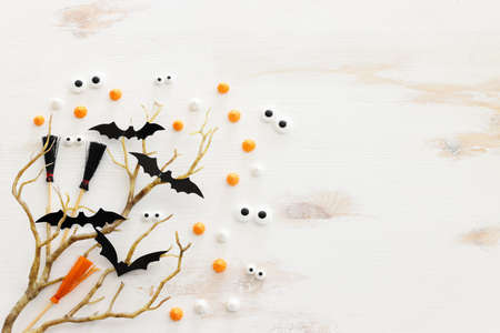 top view image of Halloween holoday. witcher broom, bare trees, treats and bats over white wooden tableの写真素材