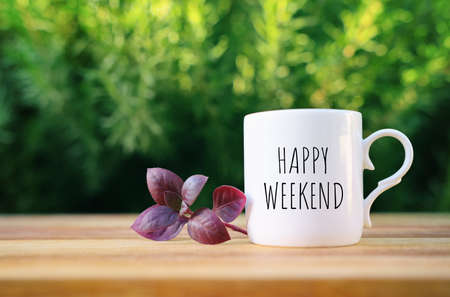coffee cup with the text happy weekend on wooden table outdoorsの写真素材