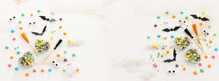 top view image of Halloween holoday. witcher broom, treats and bats over white wooden tableの写真素材