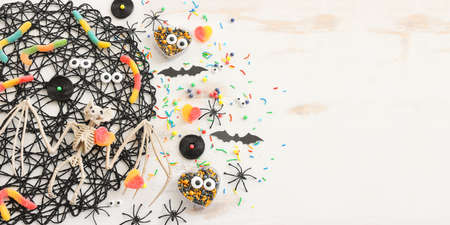 top view image of Halloween holoday. witcher broom, treats, spiders and bats over white wooden tableの写真素材