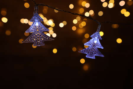 Christmas warm gold garland lights over dark background with glitter overlay