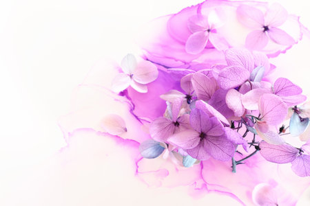 Creative image of pastel violet and pink Hydrangea flowers on artistic ink background. Top view with...
