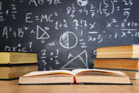 School books on desk infront of blackboard with formulas. education conceptの写真素材