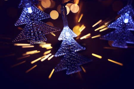 Christmas warm gold garland lights over dark background with glitter overlayの写真素材