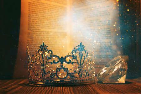 low key image of beautiful queen or king crown in front of old book. vintage filtered. fantasy medieval periodの写真素材
