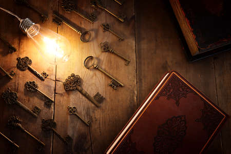 vintage key under bright lightbulb over wooden table. concept of finding the best solution