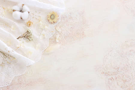 Background of white embroidered delicate lace fabric and dry flowersの写真素材