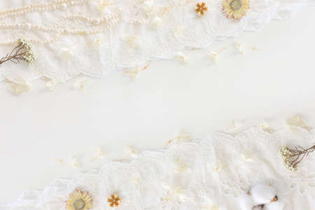 Background of white delicate lace fabric, dry flowers and pearlsの写真素材