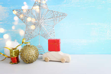 Image of christmas decorations and wooden car with present box in front of pastel blue backgroundの写真素材