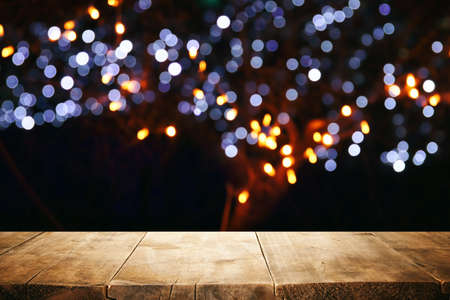 background Image of wooden table in front of abstract restaurant blurred lights